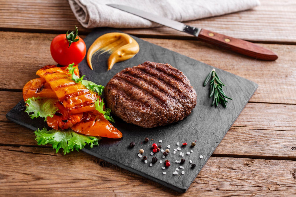 burger grill with vegetables and sauce on a wooden surface
