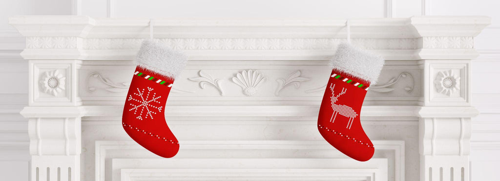 Two red christmas stockings hanging on marble stone fireplace